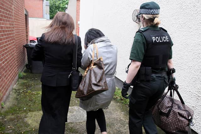 A woman, centre, is lead away by police, after they raided a house on the Lisburn Road in south Belfast during an operation against human trafficking. Photo: PA.