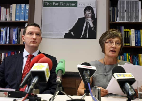 The widow of Pat Finucane, Geraldine Finucane ,and her son John, puctured in front of an image of the murdered lawyer
