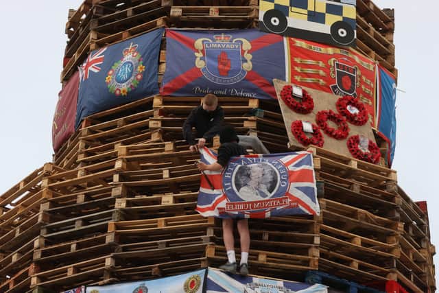 Young boys fix a union flag bearing the Queen's face to a bonfire prior to it being lit to mark the Catholic Feast of the Assumption in the Bogside area of Londonderry, Northern Ireland. Picture date: Monday August 15, 2022.