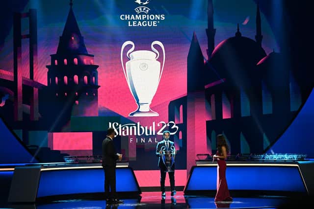 Former Turkish player Hamit Altintop (C) holds the Champions League trophy on stage before the draw