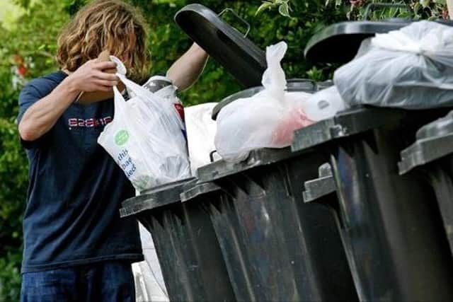 A man empties waste into a wheelie bin