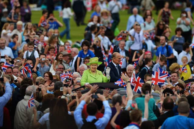 BELFAST, NORTHERN IRELAND - JUNE 27: Queen Elizabeth II and Prince Philip, Duke of Edinburgh attend a Diamond Jubilee event at Stormont on June 27, 2012 in Belfast, Northern Ireland. Thousands looked on as Queen Elizabeth II and Prince Philip, were driven around the estate in an open top vehicle on the final day of their visit. The Queen earlier shook hands with Northern Ireland's deputy first minister and former IRA commander Martin McGuinness for the first time when they met inside the Lyric theatre. The Queen and Duke of Edinburgh are on a Diamond Jubilee visit to Northern Ireland. (Photo by Jeff J Mitchell/Getty Images)
