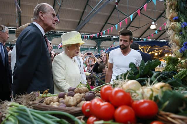 Britain's Queen Elizabeth II and Prince Philip, Duke of Edinburgh (L) talk with stall holder Simon Matthews during a visit to St George's indoor market on June 24, 2014 in Belfast, Northern Ireland..  AFP PHOTO/POOL/PETER MACDIARMID        (Photo credit should read PETER MACDIARMID/AFP via Getty Images)
