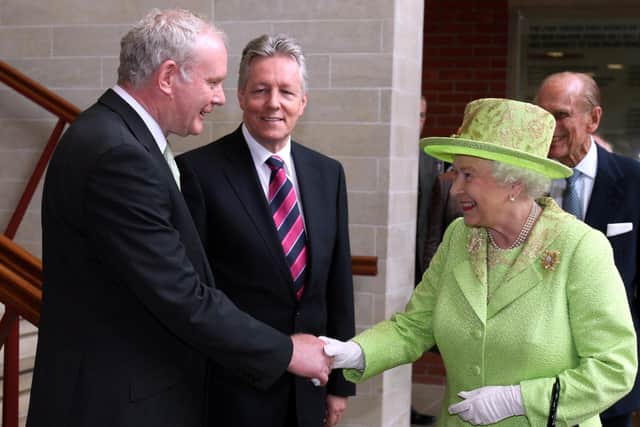 Queen Elizabeth II shaking hands with Northern Ireland Deputy First Minister Martin McGuinness watched by First minister Peter Robinson (centre) at the Lyric Theatre in Belfast. Photo credit: Paul Faith/PA Wire