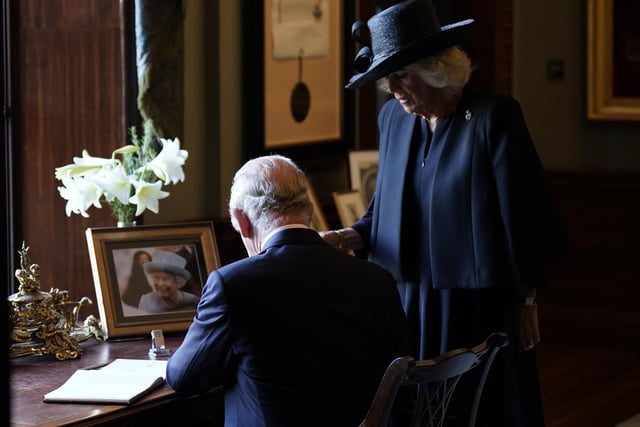 King Charles III and the Queen Consort sign the visitors book at Hillsborough Castle, Co Down