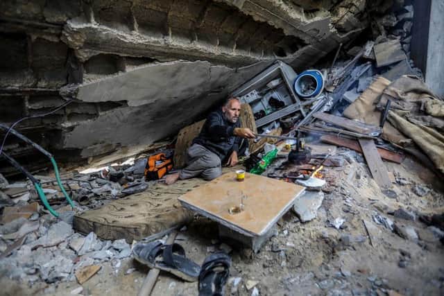 Palestinian Yassin Ahmed Al-Qara, 47, sits with his family under the rubble of his house, which was destroyed by air strikes in the Khuza’a area on November 28, 2023 in Khan Yunis, Gaza