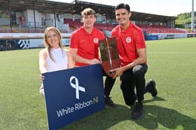 Tahnee McCorry from White Ribbon Northern Ireland pictured with Larne defenders Micheal Glynn and Shaun Want ahead of this year's Charity Shield match between the Inver Reds and Crusaders