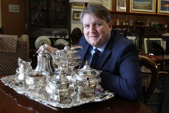 Managing director of Bloomfield Auctions, Karl Bennett, shows off a silver tea service which along with a trove of letters offer a "unique glimpse" into the private life of the late Queen Elizabeth II and are set to go under the hammer in Belfast