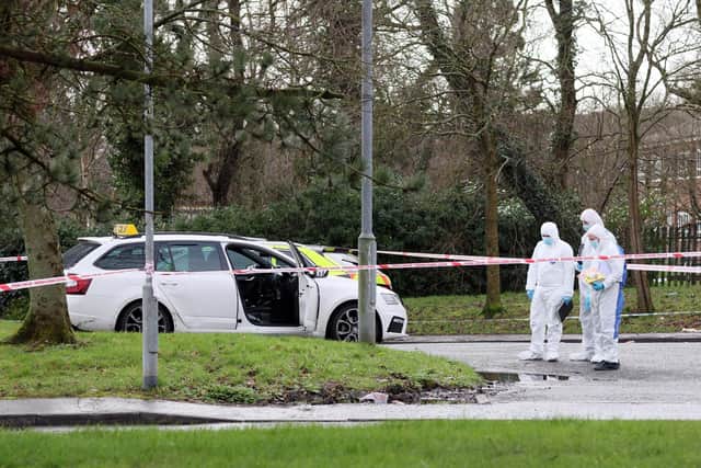 Forensic officers examine the white taxi in which a man was shot in the Poleglass area of west Belfast on Sunday morning. PICTURE BY STEPHEN DAVISON