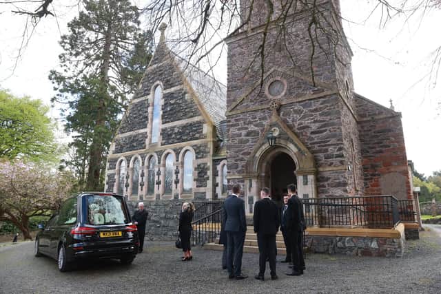 Mourners gather as the hearse carrying the coffin of former BBC Northern Ireland political editor Stephen Grimason arrives for his funeral mass at Drumbeg Parish Church in Dunmurry, Belfast