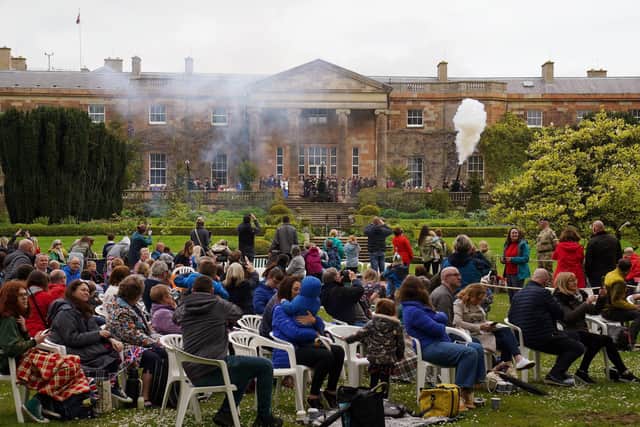 Members of the public watch a 21-gun salute being fired at Hillsborough Castle, near Belfast, to mark the coronation of King Charles III and Queen Camilla