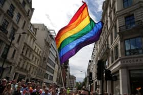 A rainbow flag is held aloft at a Pride parade.