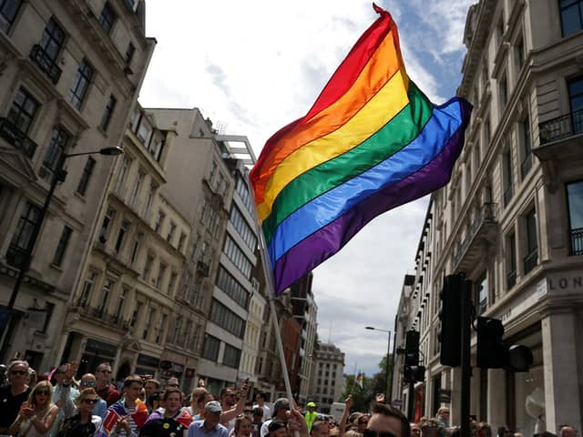 A rainbow flag is held aloft at a Pride parade.