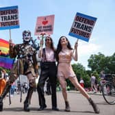 Demonstrators pose holding placards at the London Trans Pride protest, 2022