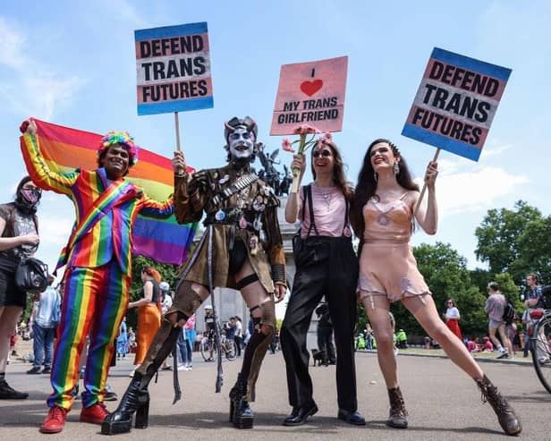 Demonstrators pose holding placards at the London Trans Pride protest, 2022