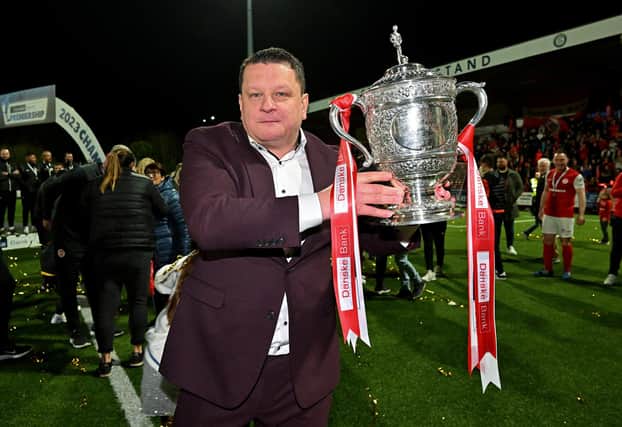 Larne owner Kenny Gibson holds the famous Gibson Cup trophy after the club secured their maiden top-flight title
