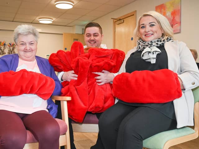 Loopland Fold resident Caroline Morrow and Housing Executive team leader Brenda Brown wrap up in hand warmers made by young people from Lagan Village Youth and Community Group in a project funded by the housing organisation. Handing the cosy gifts out to residents is Darren Leighton, from the youth group