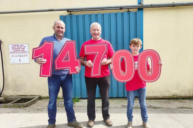 Geoffrey Murphy, Saintfield Mart auctioneer, Raffrey farmer Dee Heron and grandson Harry Heron together raised £14,700 for Action Cancer. Picture: Action Cancer