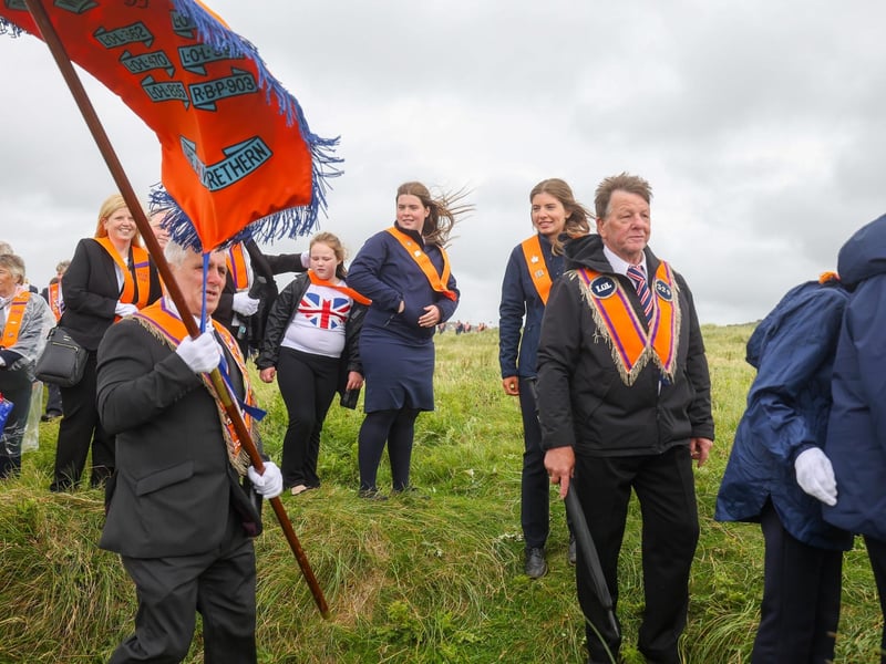 Orange men and women make their way through the dunes to the beach