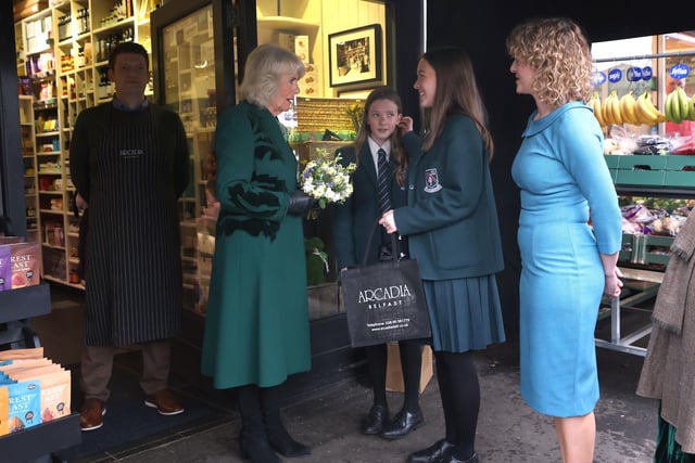 Queen Camilla is presented with posies by sisters Matilda Brown, 16 (2nd right) and Dolly Brown, 13 from Strathearn School as she leaves after a visit to Lisburn Road in Belfast to meet shop owners and staff