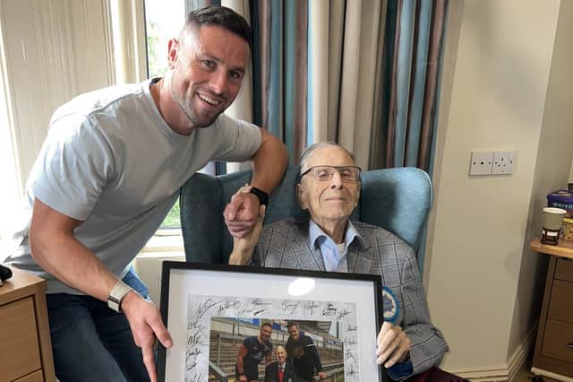 John Cooney gives Noble Hamilton a photo signed by the Ulster Rugby team for his 100th birthday