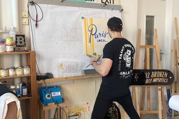 Vincent Audoin, a Parisian artisan, painting a sign in his studio.