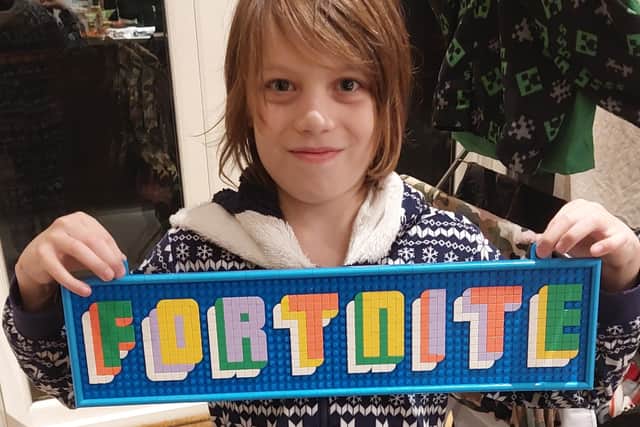 My nine-year-old son with a Fortnite sign made from Lego Dots