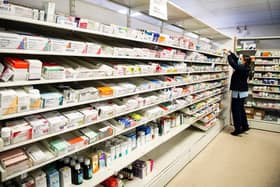 A pharmacy staff member puts in order medications in drawers and shelves