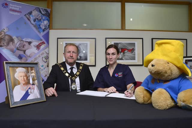 Jenny Thompson, Head of Children’s Services at the NI Children’s Hospice, signs the book of condolence for Queen Elizabeth II as Mayor of Antrim and Newtownabbey Alderman Stephen Ross watches on