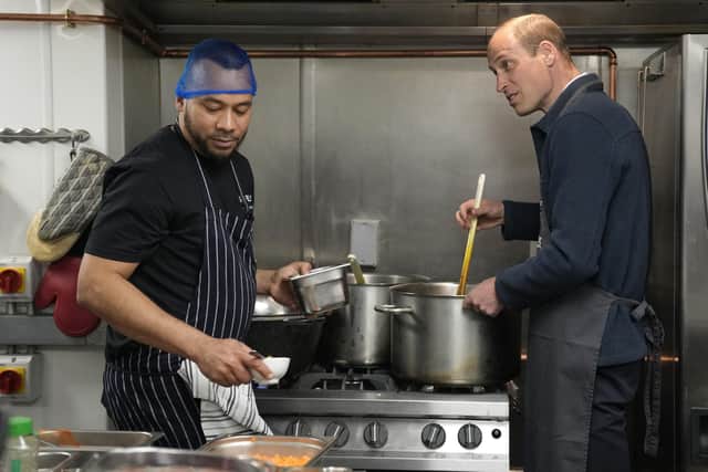 The Prince of Wales (right) helps make bolognase sauce with head chef Mario Confait during a visit to Surplus to Supper. Photo: Alastair Grant/PA Wire