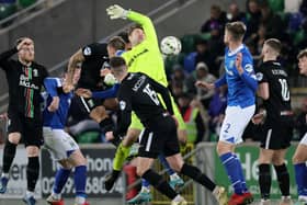 Glentoran's Danny Purkis ducks down behind Linfield's Chris Johns to head home at Windsor Park