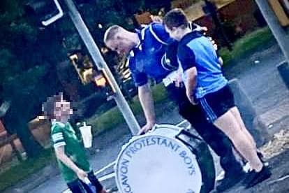 Photo of flute band drummer giving two young GAA fans a go on his bass drum goes down a storm