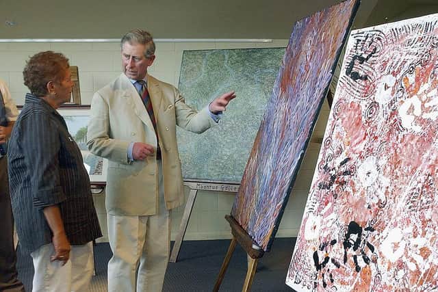 The then-Prince Charles speaks with Aboriginal local artist Barbara Wier about her paintings in Alice Springs, Australia; the King has shown a life-long interest in the arts, and paints watercolours himself