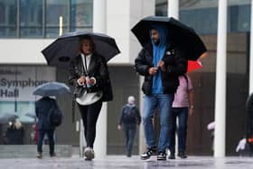 People walk by Centenary Square in Birmingham during a rainy morning
