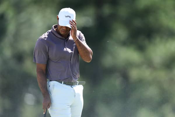 Tiger Woods shields his face from the blowing sand on the 18th green during the second round of the Masters at Augusta National. (Photo by Warren Little/Getty Images)