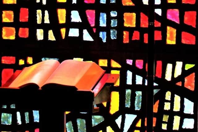 Generic image of an open Bible against stained glass. Image from Creative Commons (Project 365, 87, 280314: Crying In The Chapel, by comedynose, is marked with Public Domain Mark 1)