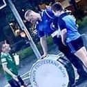 A member of Craigavon Protestant Boys Flute Band allows a child wearing a GAA top to hit his bass drum during a band parade in Cookstown