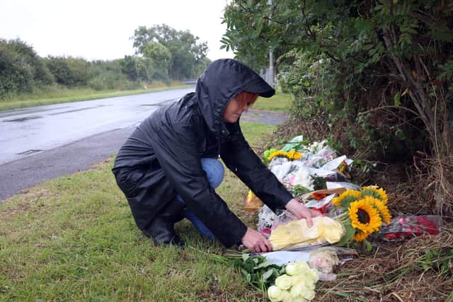A woman lays flowers at the scene where racer, Alan Connor and marshal, Liam Clarke, died in a crash during practice for the Southern 100 motorcycle races on the Isle of Man on Tuesday night. Picture: Stephen Davison/Pacemaker Press