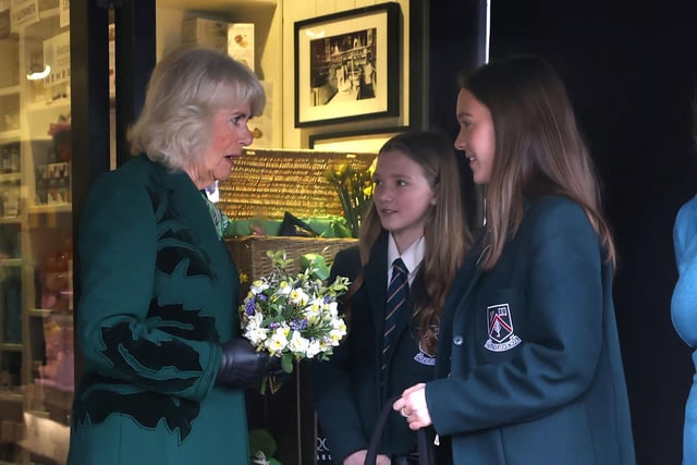 Queen Camilla is presented with posies by sisters Matilda Brown, 16 (right) and Dolly Brown, 13 from Strathearn School