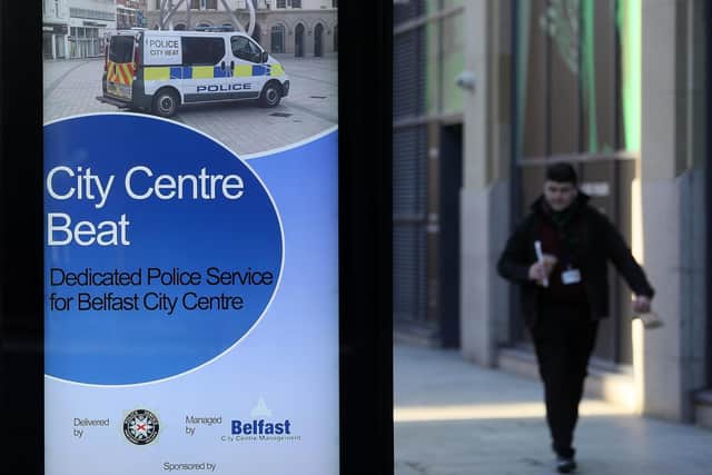 A man walks past an ad for policing in Belfast city centre on a quiet street as the six week lockdown in Northern Ireland continues.