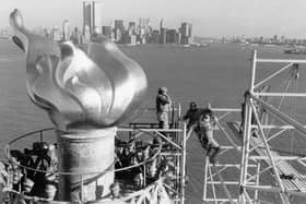 Workers remove 17 December 1985 scaffolding from around the torch of the Statue of Liberty, one of the world's most famous landmarks,  with Manhattan skyline and the twin towers of the World Trade Center in the background.

afp photo /paul demaria (Photo by - / AFP) (Photo by -/AFP via Getty Images)