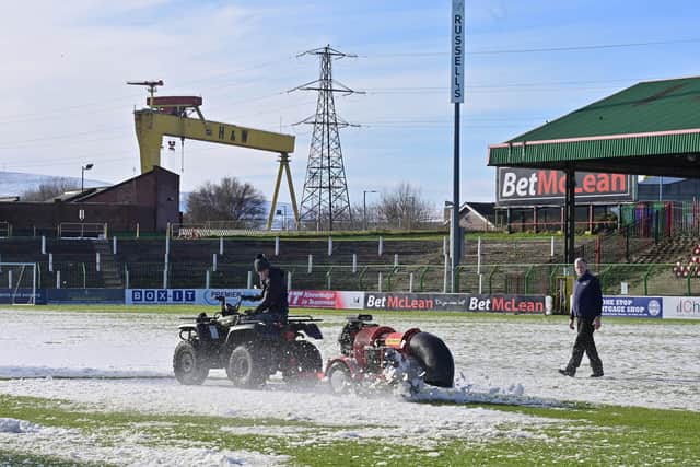 Volunteers clear snow from the pitch on Friday at The Oval