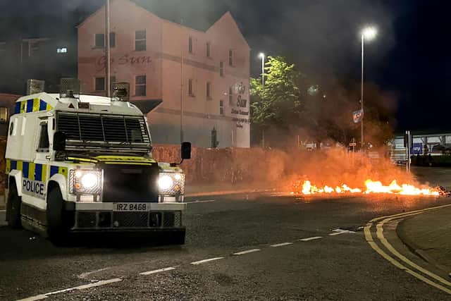 A PSNI vehicle near to flaming debris on fire during a third night of disorder in Ballymena. Petrol bombs, a hatchet and masonry were among items thrown at police, who responded with water cannon, dogs and plastic baton rounds in an attempt to disperse crowds in the Co Antrim town. Photo: Liam McBurney/PA Wire