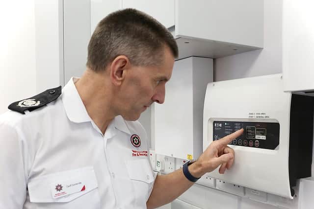 Northern Ireland Fire & Rescue Service Group Commander Geoff Somerville inspects an automatic fire alarm system.