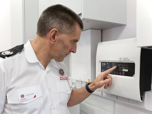 Northern Ireland Fire & Rescue Service Group Commander Geoff Somerville inspects an automatic fire alarm system.