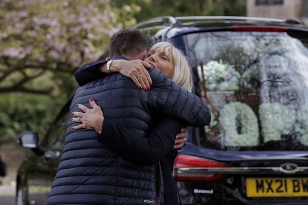 Mourners embrace each other as the hearse, carrying the coffin of former BBC Northern Ireland political editor Stephen Grimason, arrives for his funeral mass at Drumbeg Parish Church in Dunmurry, Belfast. Pic: Liam McBurney/PA Wire