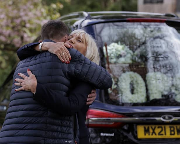Mourners embrace each other as the hearse, carrying the coffin of former BBC Northern Ireland political editor Stephen Grimason, arrives for his funeral mass at Drumbeg Parish Church in Dunmurry, Belfast. Pic: Liam McBurney/PA Wire