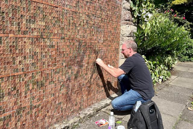 Mark uses nail polish remover and cotton wool pads to clean the graffiti off the memorial. Pic: John Baucher