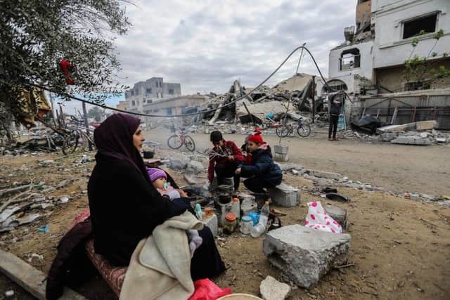 KHAN YUNIS, GAZA - NOVEMBER 28:  A family gathers around a fire in front of the rubble of their home, which was destroyed by air strikes in the Khuza’a area on November 28, 2023 in Khan Yunis, Gaza. A temporary ceasefire between Israel and Hamas has held since Friday, offering Gaza residents respite from constant bombardment. The Hamas-run health ministry in Gaza says that over 14,500 people in Gaza have been killed since Oct. 7, when Israel launched a military offensive in retaliation for Hamas's deadly cross-border attacks. (Footage by Ahmad Hasaballah/Getty Images)