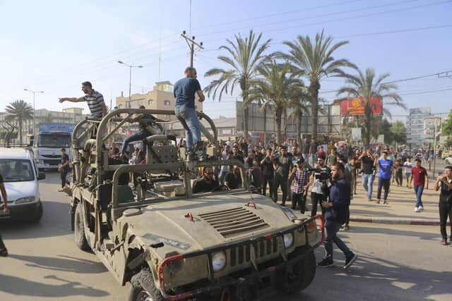 Palestinians ride on an Israeli military vehicle taken by an army base overrun by Hamas militants near the Gaza Strip fence, in Gaza City, Saturday, Oct. 7, 2023. (AP Photo/Abed Abu Reash)